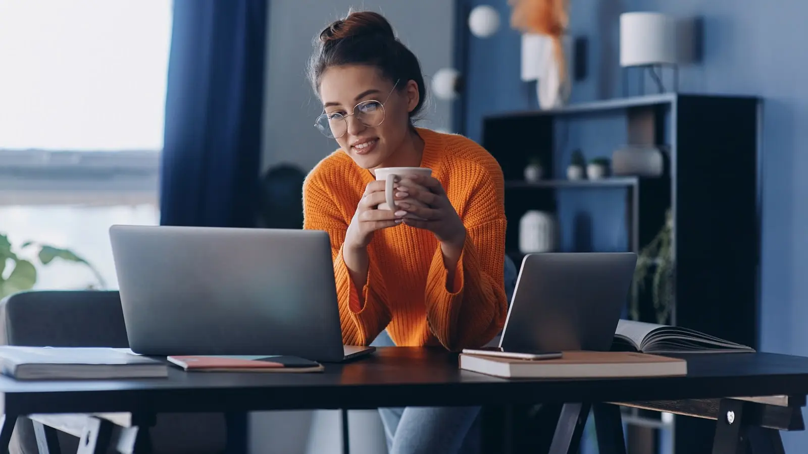 A young attractive women is sitting in her home office at the laptop searching for jobs